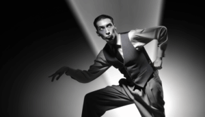 alt_text: Walton Goggins in a dynamic pose, embodying film noir and western themes with dramatic lighting.